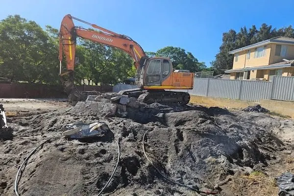 Excavator on a cleared block after a house demolition